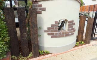 既存の塀と新設の跳ね上げ門扉の間をつなぐ塗り壁